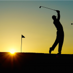 man playing golf with sunset in the background